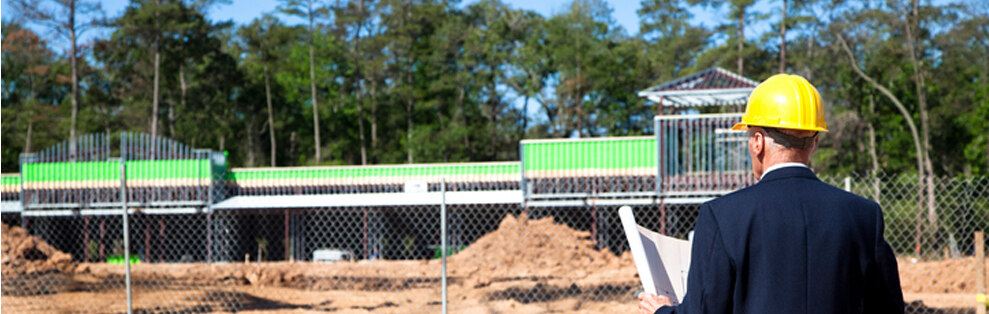 main in front of construction site looking at blueprints