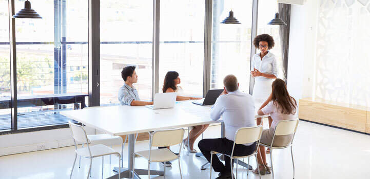 Five working professionals attending a meeting in a conference room.