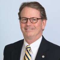 Steve Andrews dressed in business attire smiling to a camera.