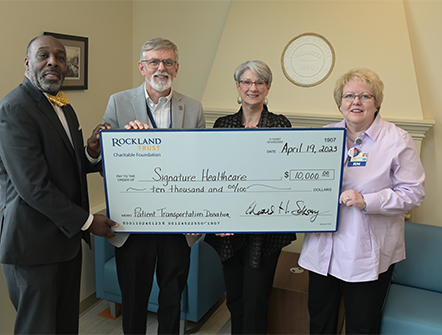 Members of Signature Healthcare posing with their giant check from Rockland Trust's Charitable Foundation.